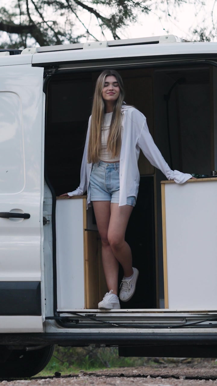 Young Woman Standing in Open Camper Van Door