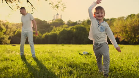 Young-father-with-his-little-son-playing-football-on-football-pitch