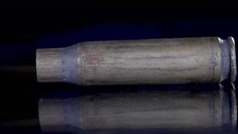 close-up of a recently fired bullet shell lying on the ground with smoke coming out