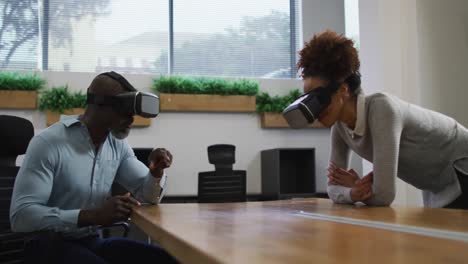 diverse male and female business colleagues wearing vr headsets in office