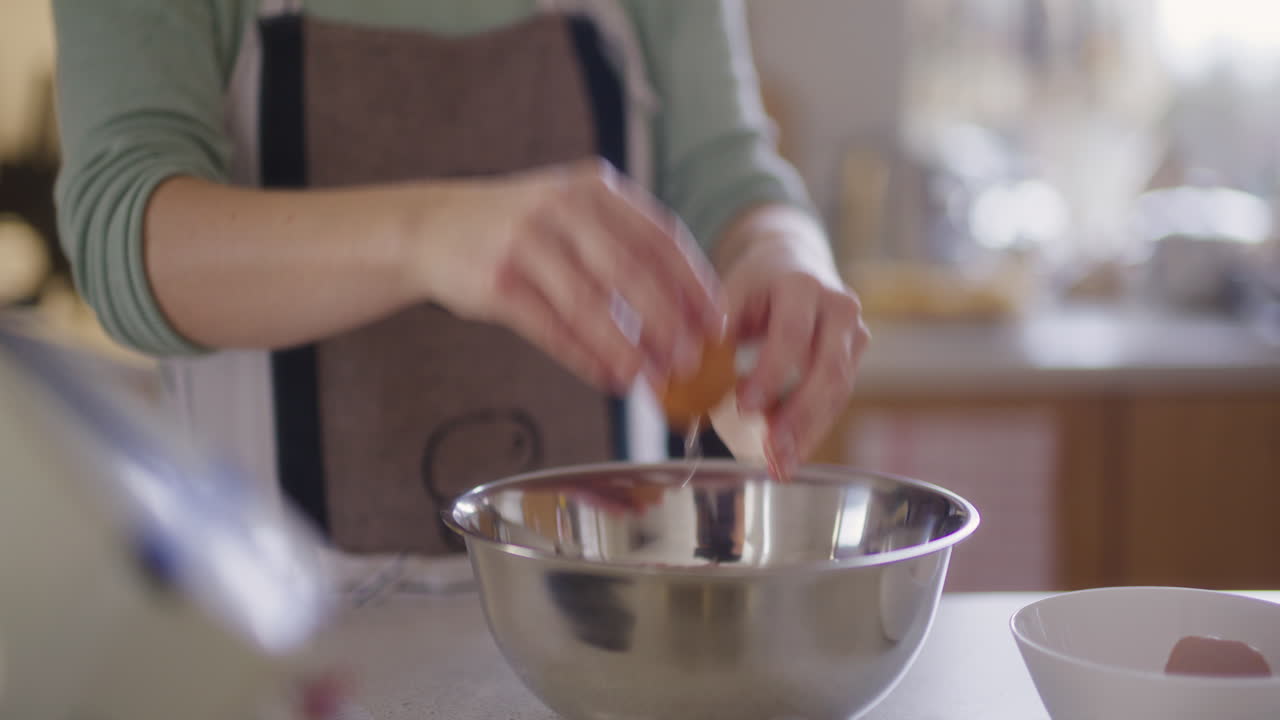 Close-up of cracking raw egg into bowl preparing dough