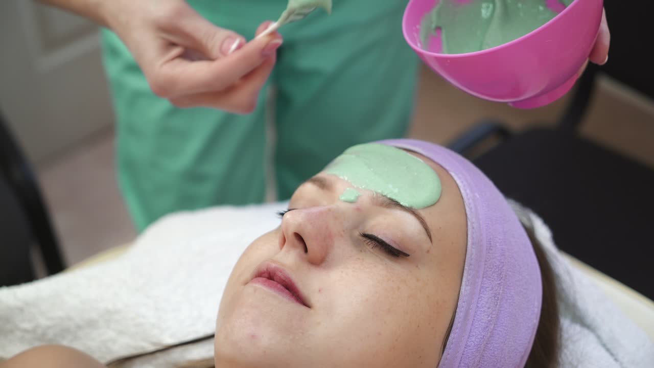 Woman getting facial mask in spa. Young woman in the mask cosmetic procedure in spa salon