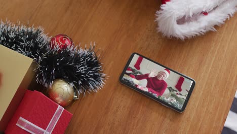 Hombre-Afroamericano-Albino-Sonriente-Con-Sombrero-De-Papá-Noel-En-Videollamada-Navideña-En-Un-Teléfono-Inteligente