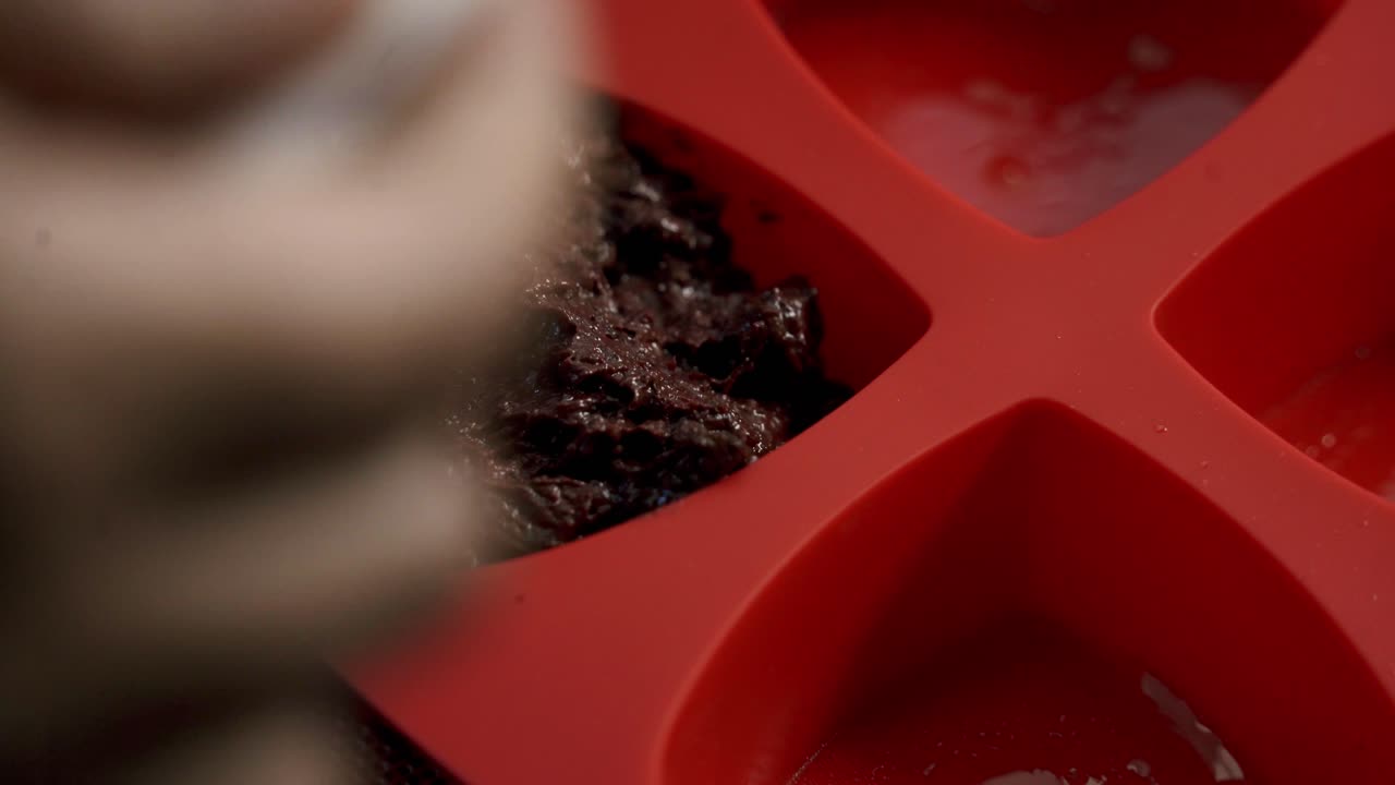 Splendida ripresa dell'impasto per torta di brownie, cioccolato e muffin alle barbabietole che viene versato in una teglia da forno in silicone rossa