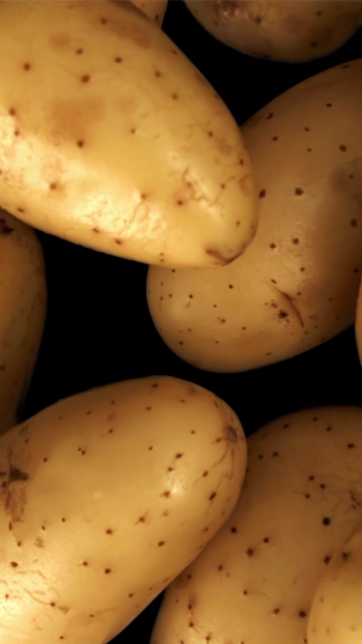 Patate fresche crude su sfondo nero con zoom indietro