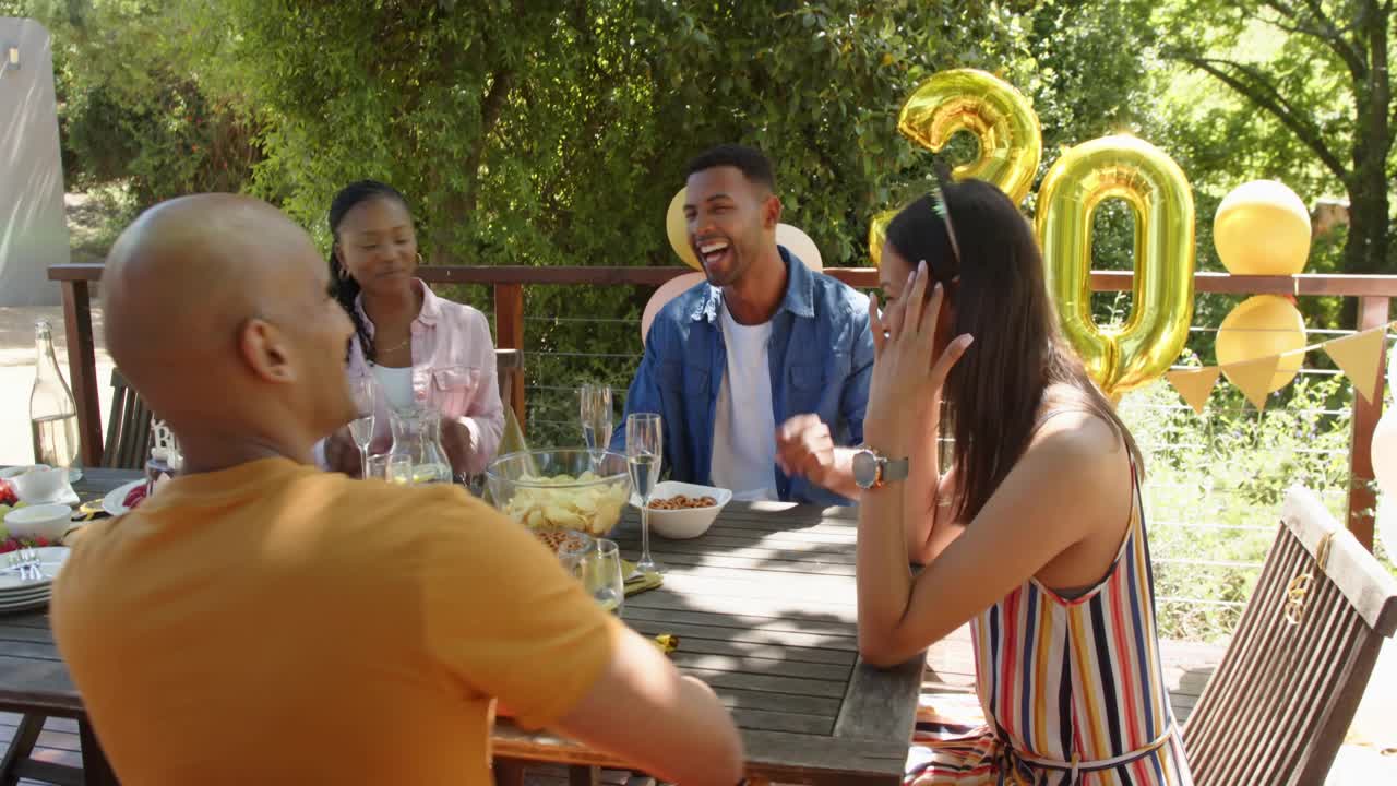 Four friends clapping after blue-shirt speaking birthday, gold 30, green flare hiding faces, events