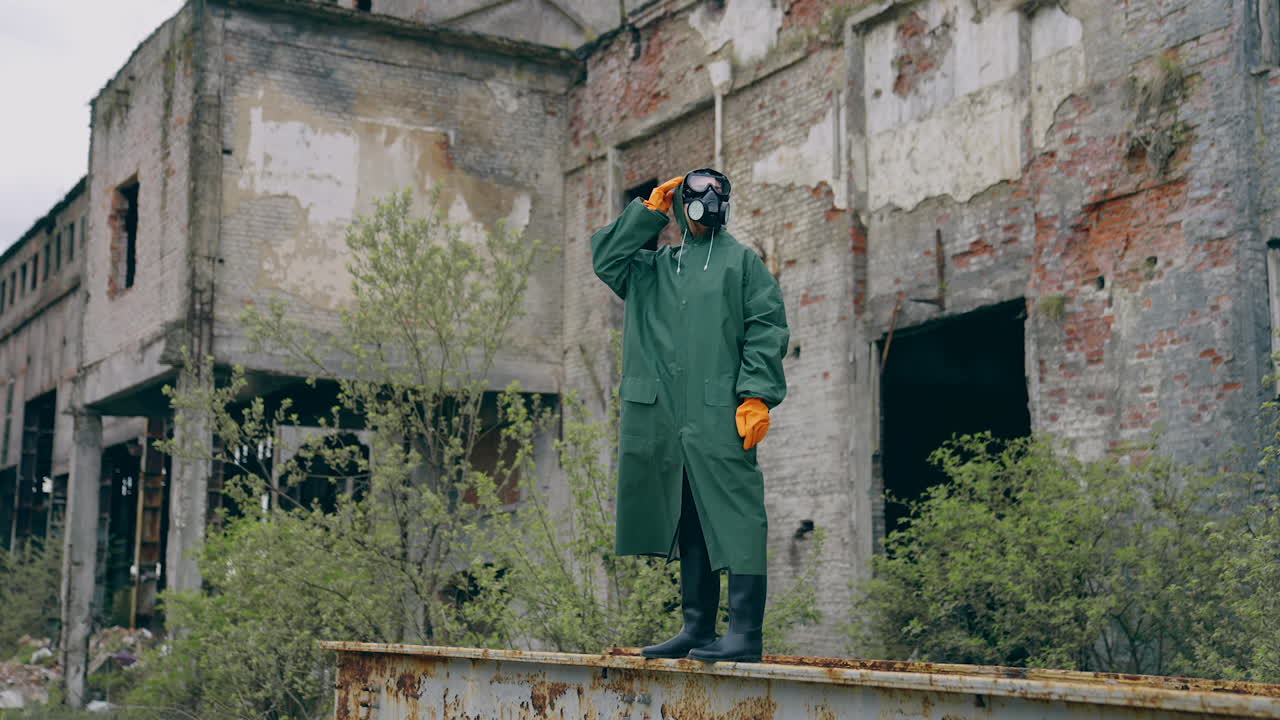Man in protective mask on ruins. Dramatic portrait of man wearing gas mask near ruined building