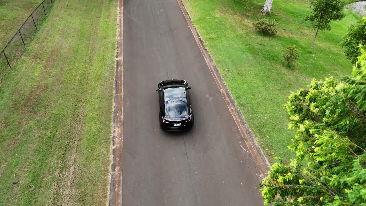 나무로 둘러싸인 도로에서 테슬라의 공중 사진