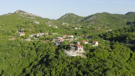 drone flying away from hidden rural village in skadar lake montenegro hidden between trees