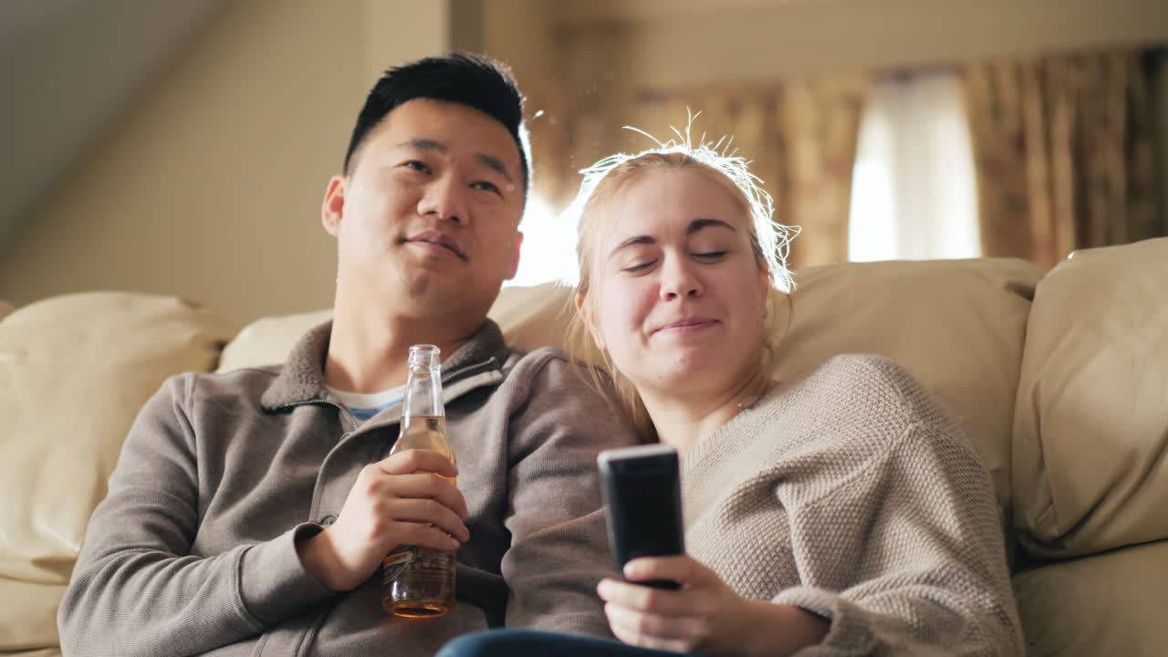 맥주를 마시는 tv 남자를 보는 젊은 부부