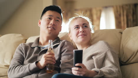맥주를 마시는 tv 남자를 보는 젊은 부부