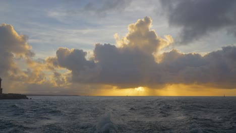 boat's rear view, entering port, massive sunset clouds with god rays