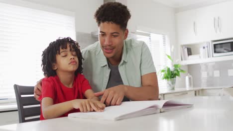happy biracial man and his son reading braille together