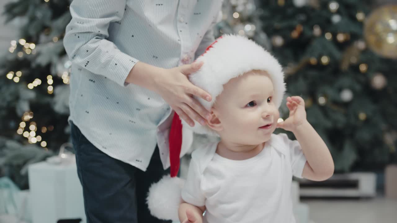 거실에서 산타 모자를 미루고 있는 어린 소년. 크리스마스 모자를 쓰고 있는 형