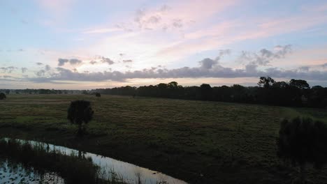 Reverse-Dolly-Aus-Der-Luft-Von-Feuchtgebieten-In-Florida,-Reflektierendes-Stilles-Wasser-Bei-Sonnenaufgang,-Gras-Zu-Wasser