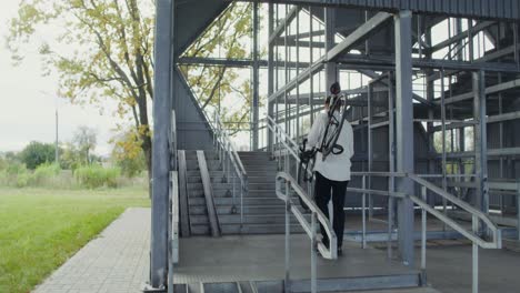 person carrying a bicycle up metal stairs