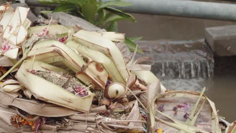 Canang-Sari---Bali-Offerings-By-Balinese-Hindus-In-A-Shrine-In-Indonesia-With-Flowing-Water-In-Background---close-up