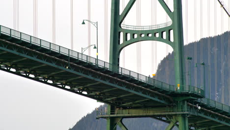 lions gate suspension bridge in stanley park, vancouver, bc, canada with person and cars passing by