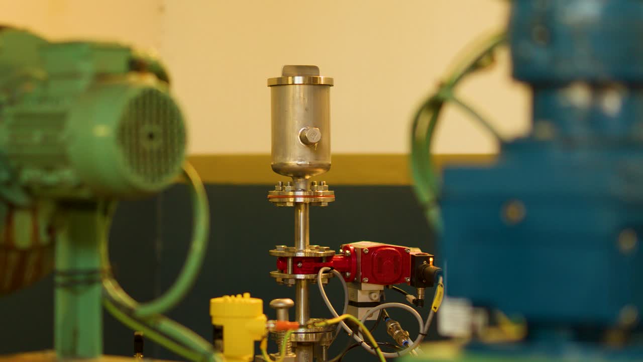 Static close-up of electric motors and valve assemblies in brightly lit industrial interior, minimal movement