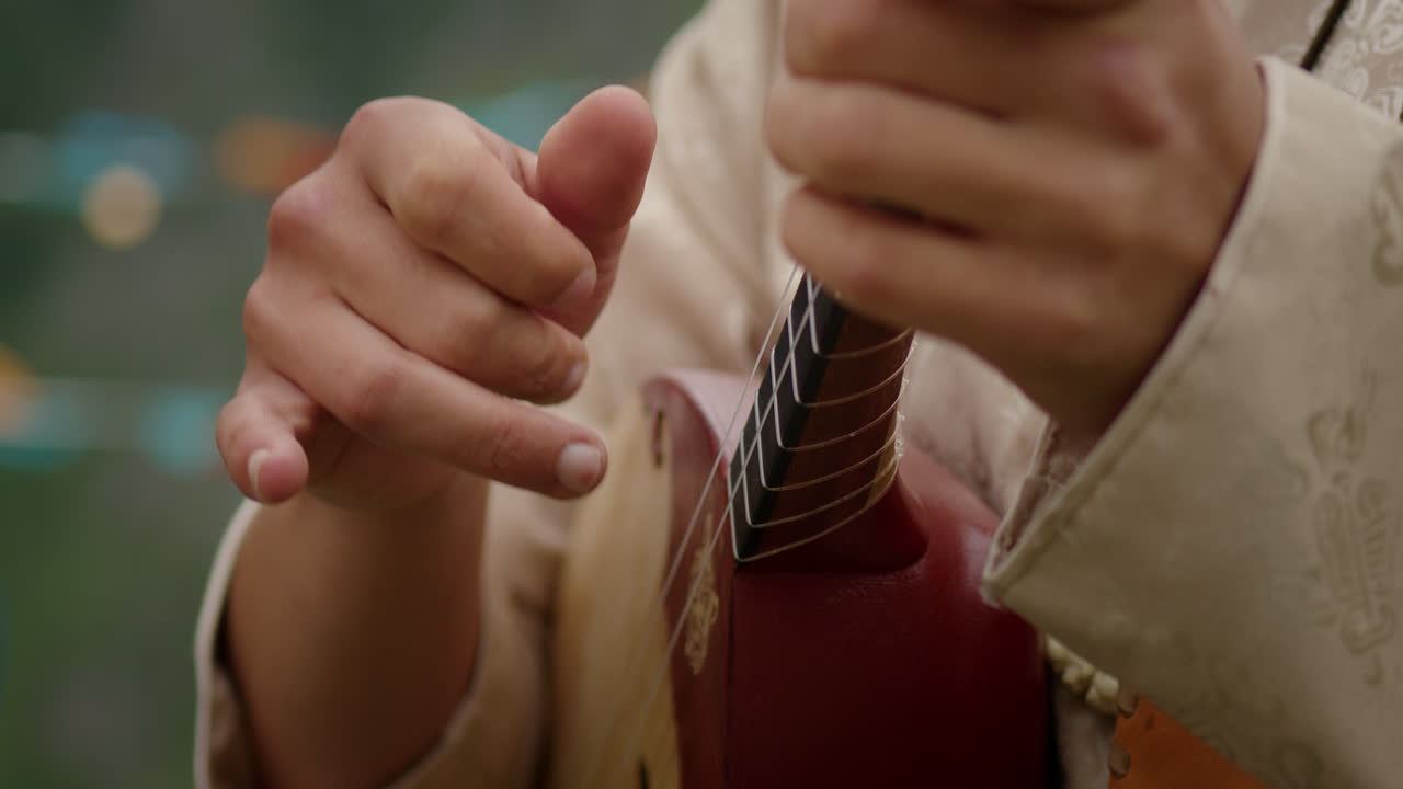 Man playing local Altay's musical string instrument on the green field. Close up shot.
