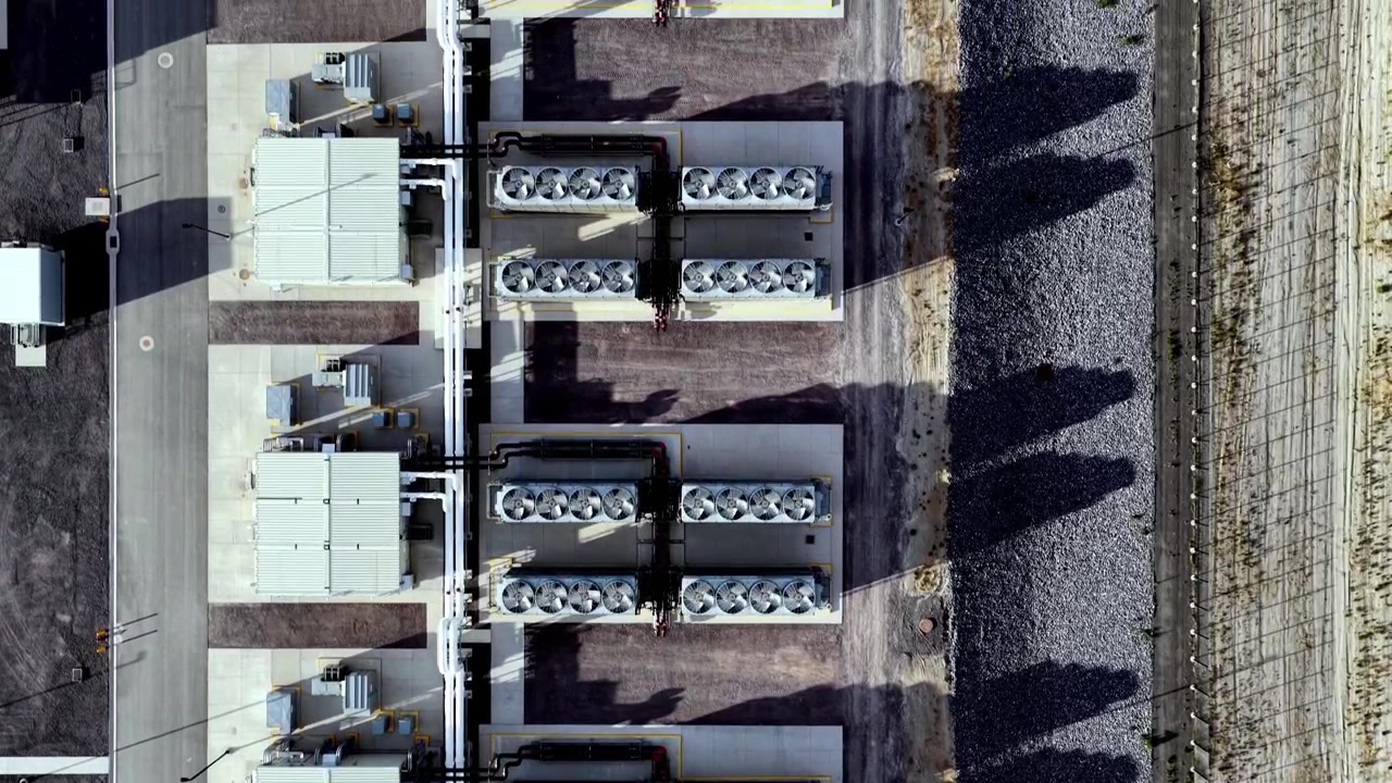 Straight-down aerial perspective of massive ventilation fans on hyperscale data center rooftops, highlighting industrial cooling systems, geometry, textures, and sharp golden hour shadows.