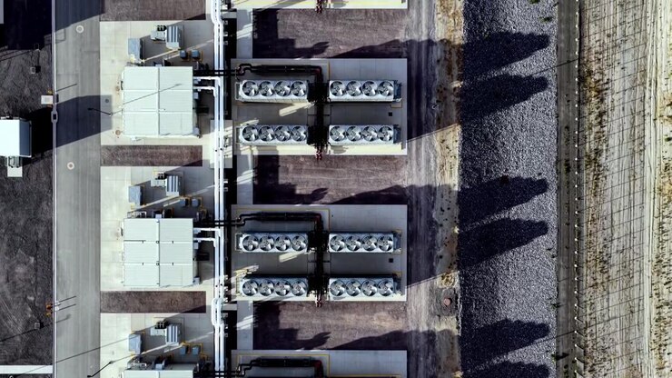 Straight-down aerial perspective of massive ventilation fans on hyperscale data center rooftops, highlighting industrial cooling systems, geometry, textures, and sharp golden hour shadows.