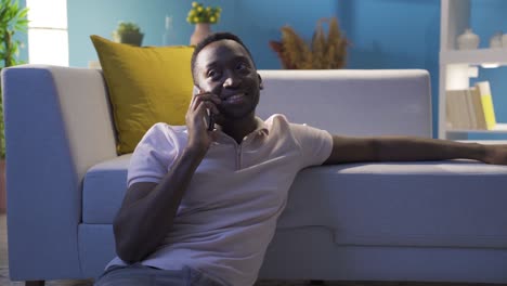 african young man talking on the phone alone at night at home.