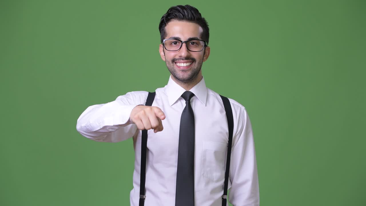 joven empresario persa barbudo y guapo contra un fondo verde