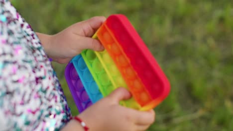 Child-girl-playing-colorful-squishy-silicone-bubbles-sensory-toy-simple-dimple-pop-it-game,-close-up