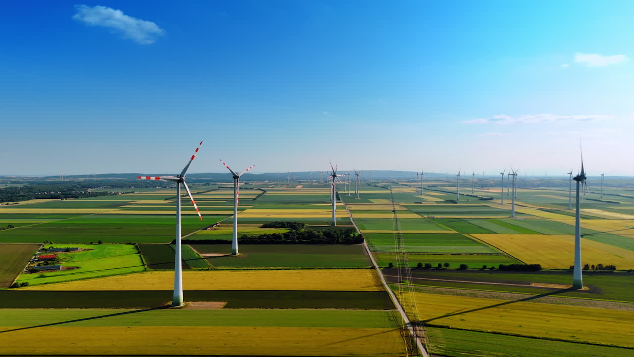 Beautiful fields of diverse shades of green. Wind turbines rotate in the wind slowly. Aerial view