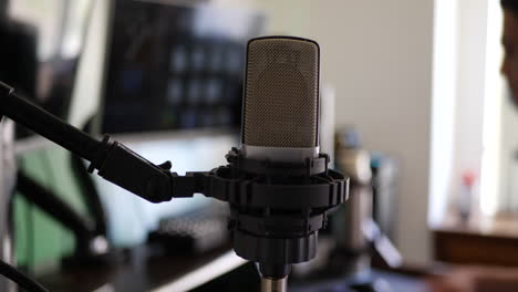 a male music producer at his music recording studio desk with a condenser microphone for recording a singer or vocalist