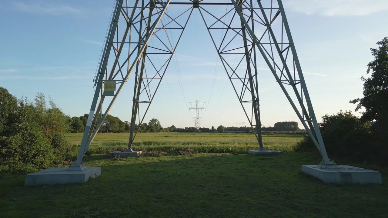 Detailed shot of a large electricity transmission pylon standing over farmland.