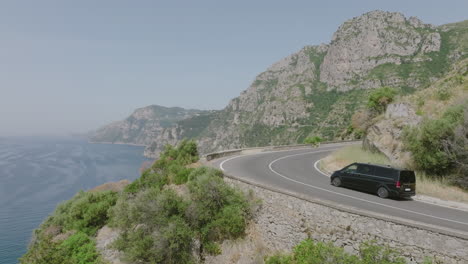 fast aerial footage following a passenger van as they drive on the amalfi coast road