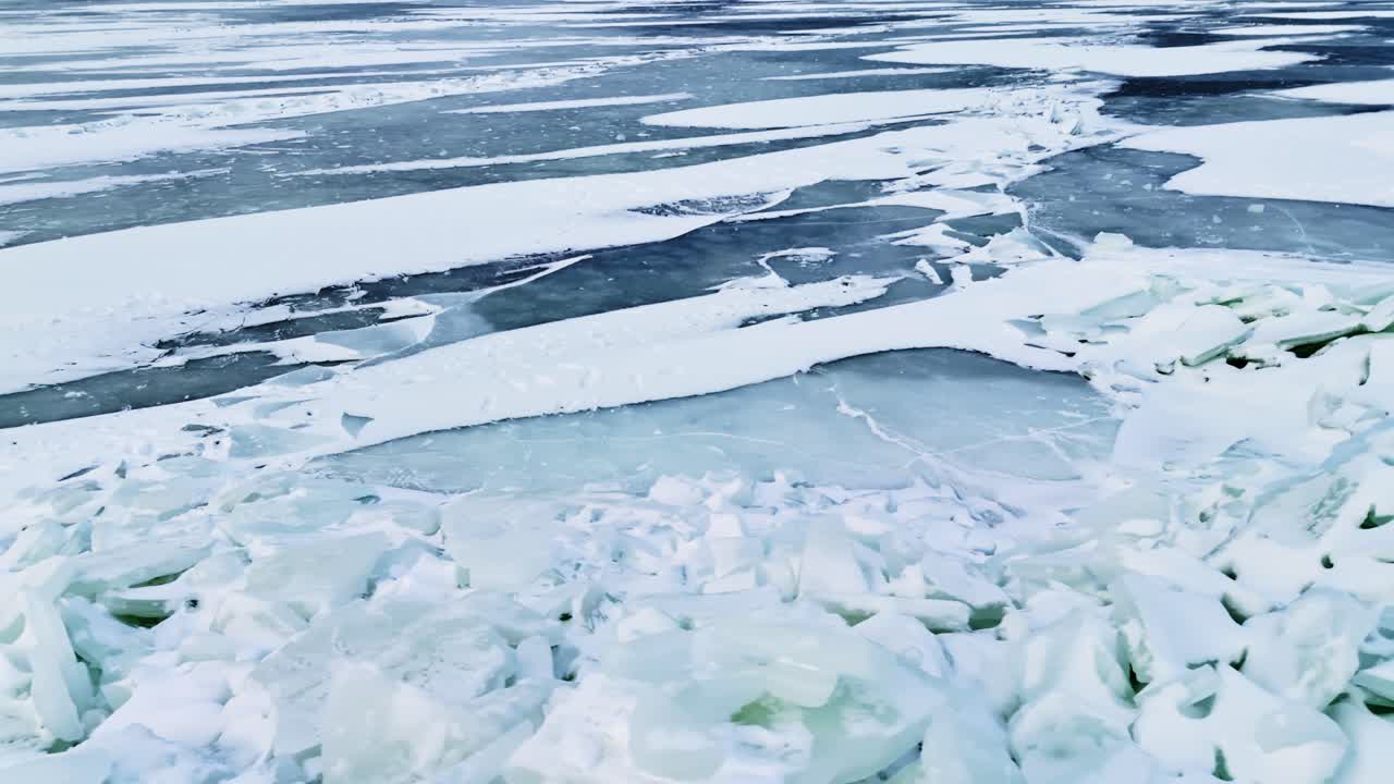 Vista de dron de hielo marino en capas y bloques rotos de crestas de presión con superficie helada agrietada que se extiende hasta el horizonte en un frío paisaje invernal