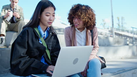 Young Female Colleagues Working with Laptop and Talking Outdoors