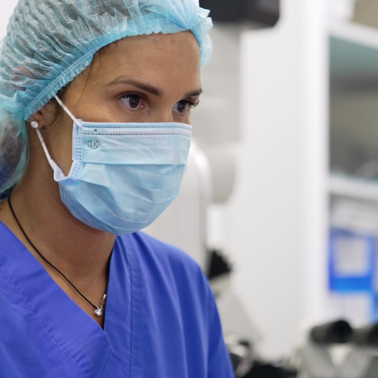 Primer plano del rostro concentrado de una doctora con mascarilla y gorro. Neuróloga usando un ordenador.