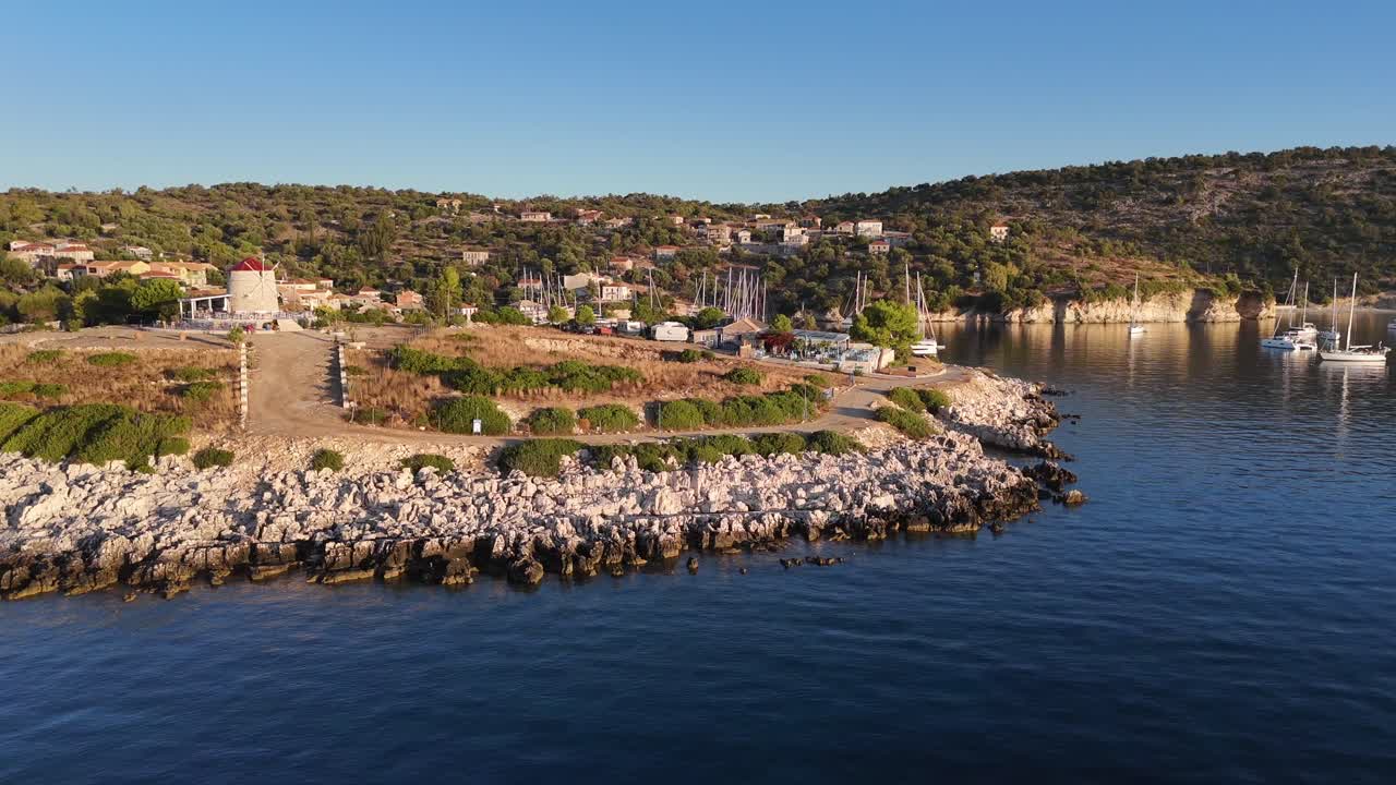 Kastos Island,aerial view forward and pan right overseeing the wind mill cafe and the harbor on a sunny day.Lot of boats at the town quay and outside on anchor