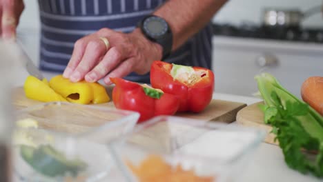 de manos de un hombre caucásico mayor cortando verduras en la cocina
