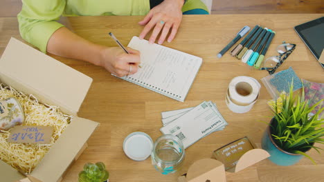 overhead shot of woman running online business making candles packaging them for dispatch