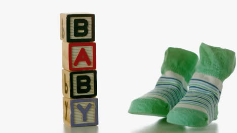 green slippers falling besides baby blocks