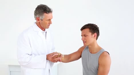 Arzt-Untersucht-Das-Verletzte-Handgelenk-Des-Sportlers