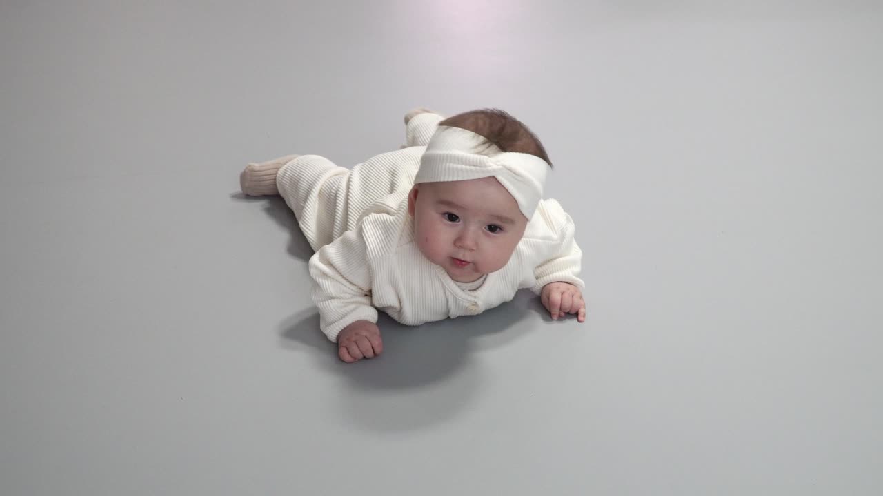 Adorable Baby Girl Playing With Her Hands While Lying On Her Stomach - high angle shot