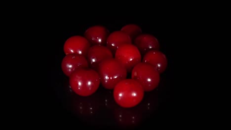rotación de primer plano cerezas rojas sobre un fondo negro.