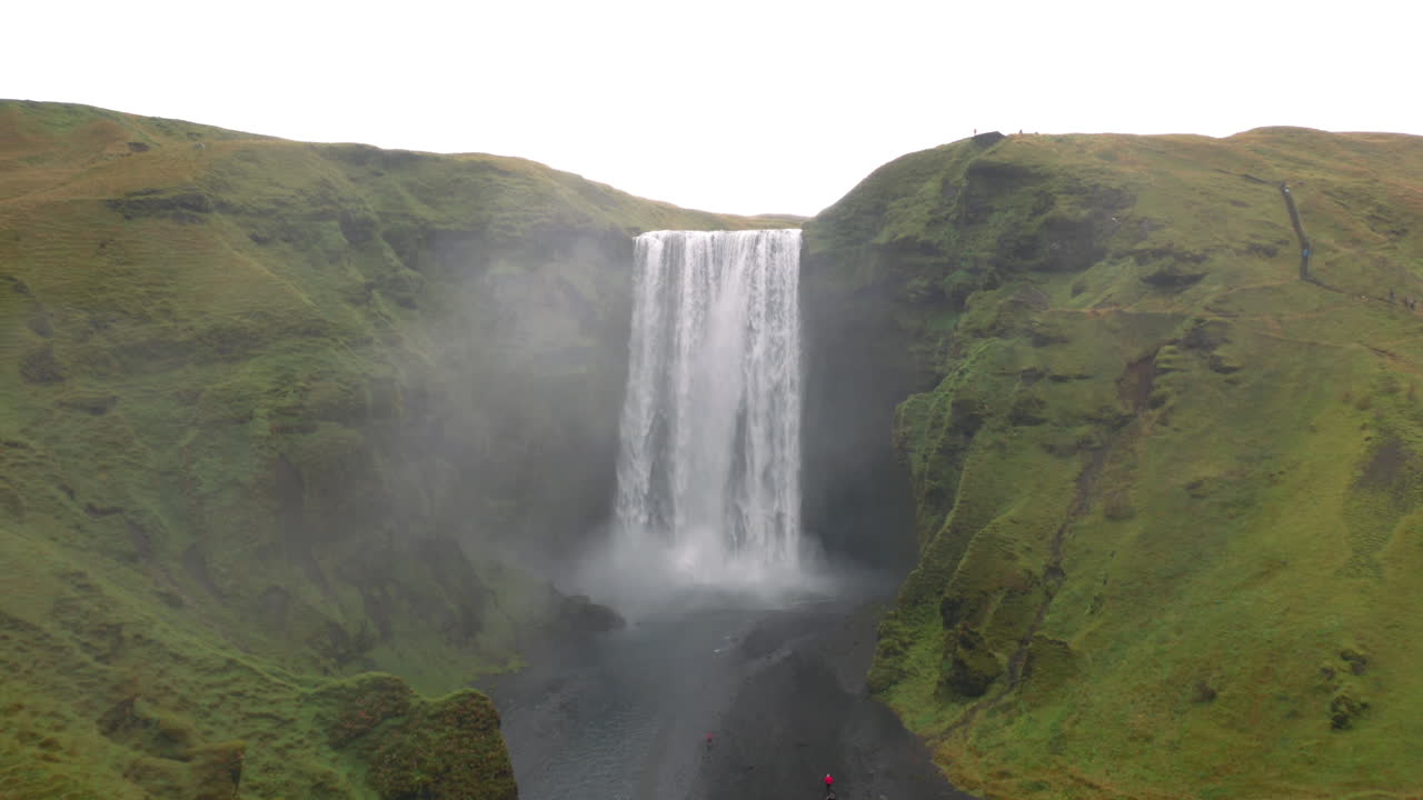 volando lejos de la cascada de skogafoss en islandia en un día nublado