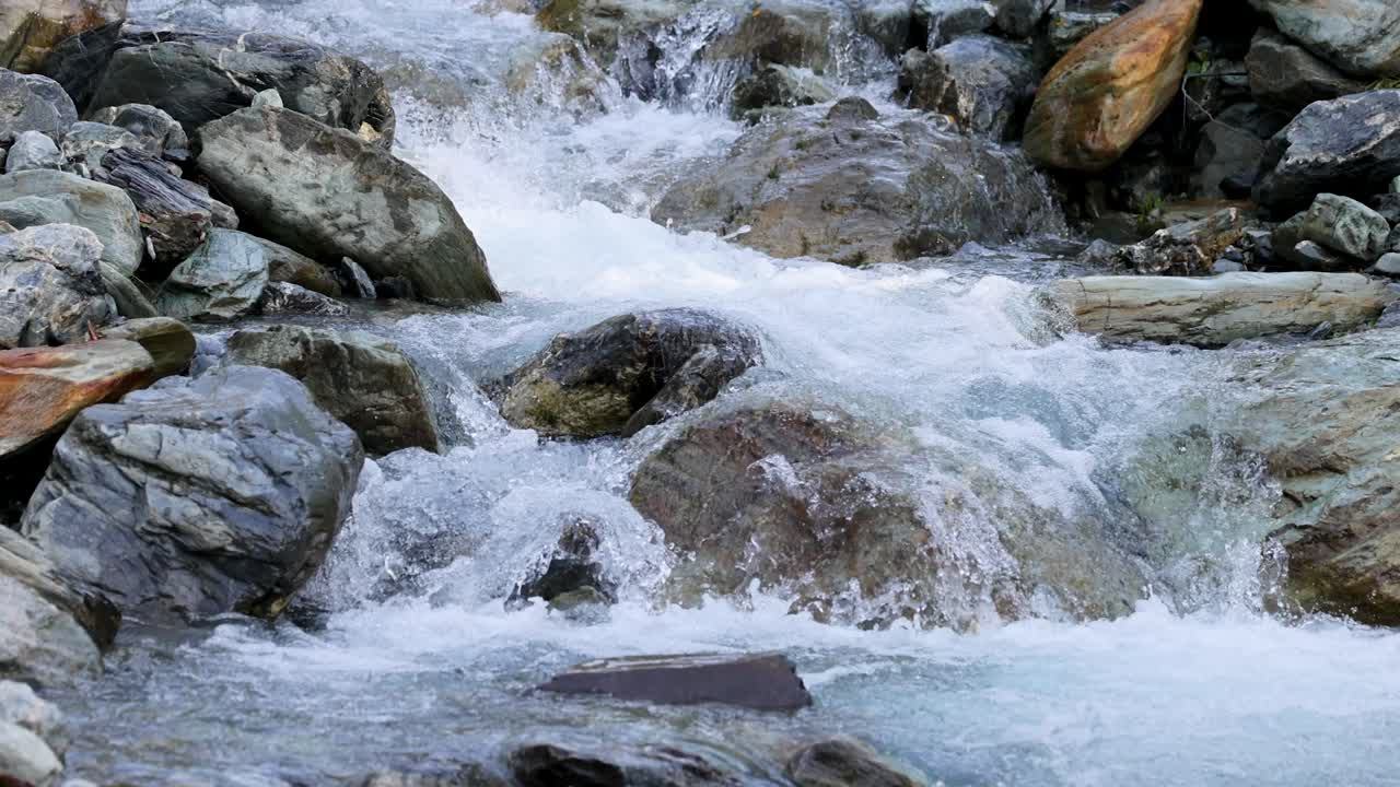 Clear mountain stream rapidly flows over large rocks in a natural outdoor setting, captured with steady camera and natural daylight for a crisp, detailed look