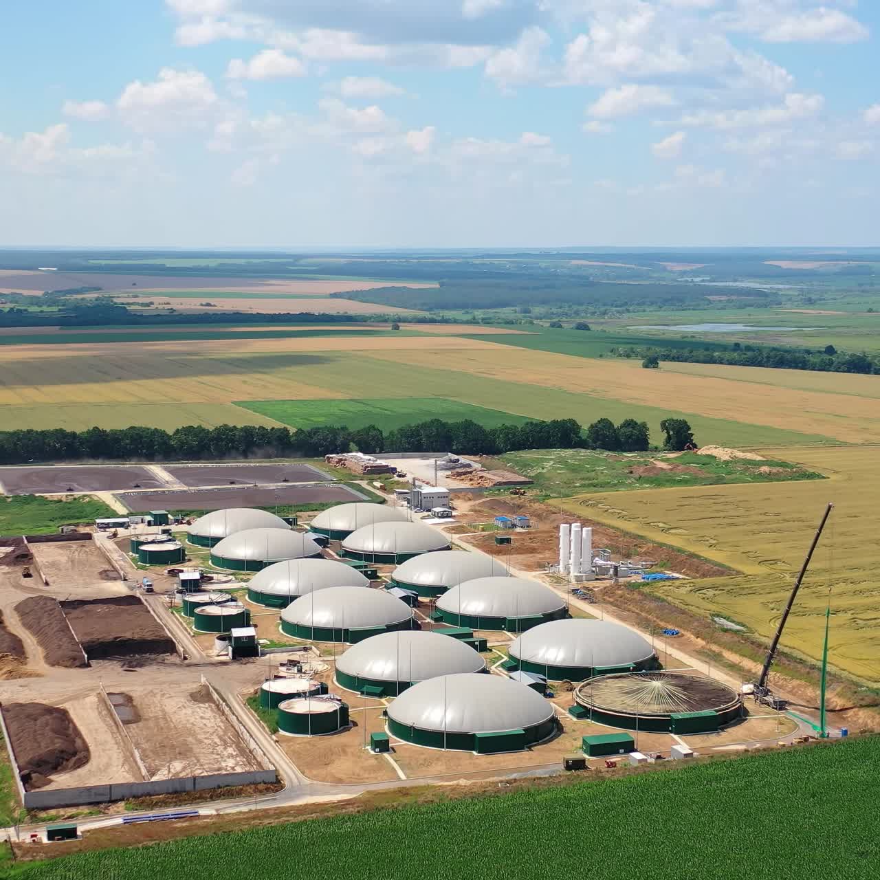 Production of biogas. New plant constructed on fields. Renewable energy from biomass. Modern agriculture complex in nature. Aerial view