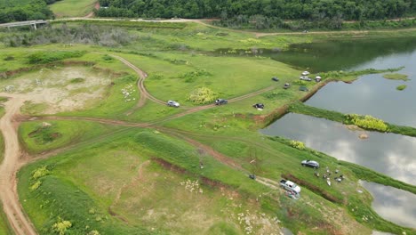 aerial footage revealing boats, vehicles parked and moving and the edge of the forest, people fishing and having picnic, muak klek, saraburi, thailand