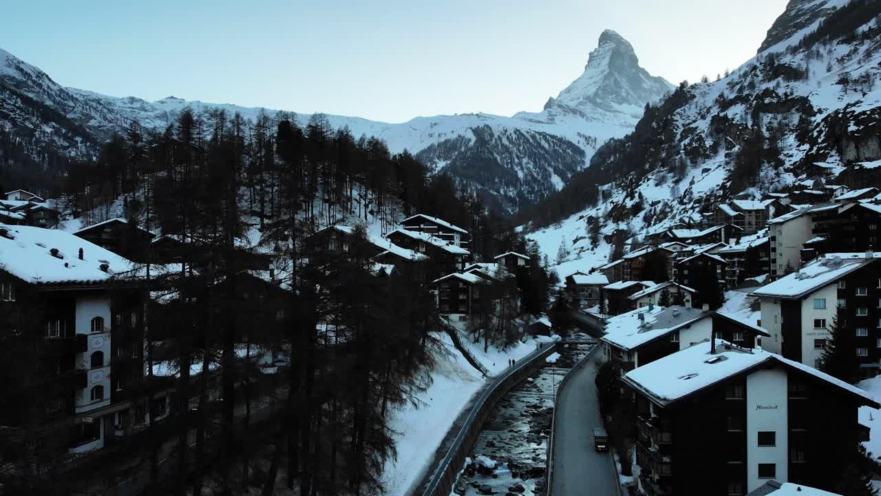 sobrevuelo aéreo sobre zermatt junto al río con vistas al matterhorn durante una puesta de sol de invierno