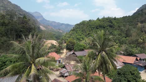 Drone-shot-of-poalm-trees-in-a-small-village-in-the-mountain-town-of-Nong-Khiaw-in-Laos,-Southeast-Asia