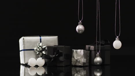 video of silver baubles christmas decorations and gifts with copy space on black background